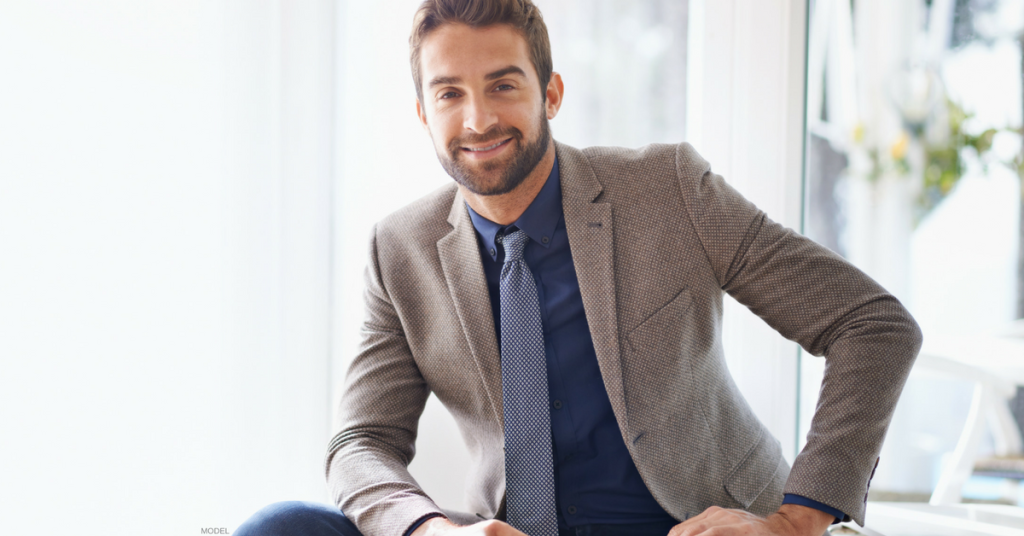 Young man with close shaven beard wearing a grey suit